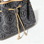 Tory Burch | Dark washed denim bucket bag with side pockets and drawstring closure featuring a T-print pattern