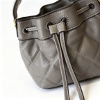 Tory Burch Willa | Grey-brown lambskin leatheradorned with a gold double-T logo detachable chain shoulder strap  drawstring closure  women's designer handbag