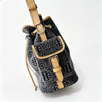 Tory Burch | Dark washed denim bucket bag with side pockets and drawstring closure featuring a T-print pattern