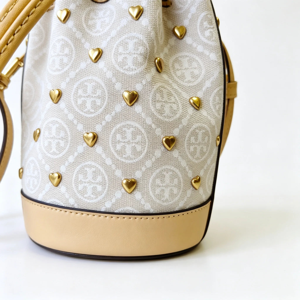 Tory Burch T Monogram ivory and beige Monogram canvas adorned with gold heart studs drawstring closure and detachable shoulder strap women's designer handbag