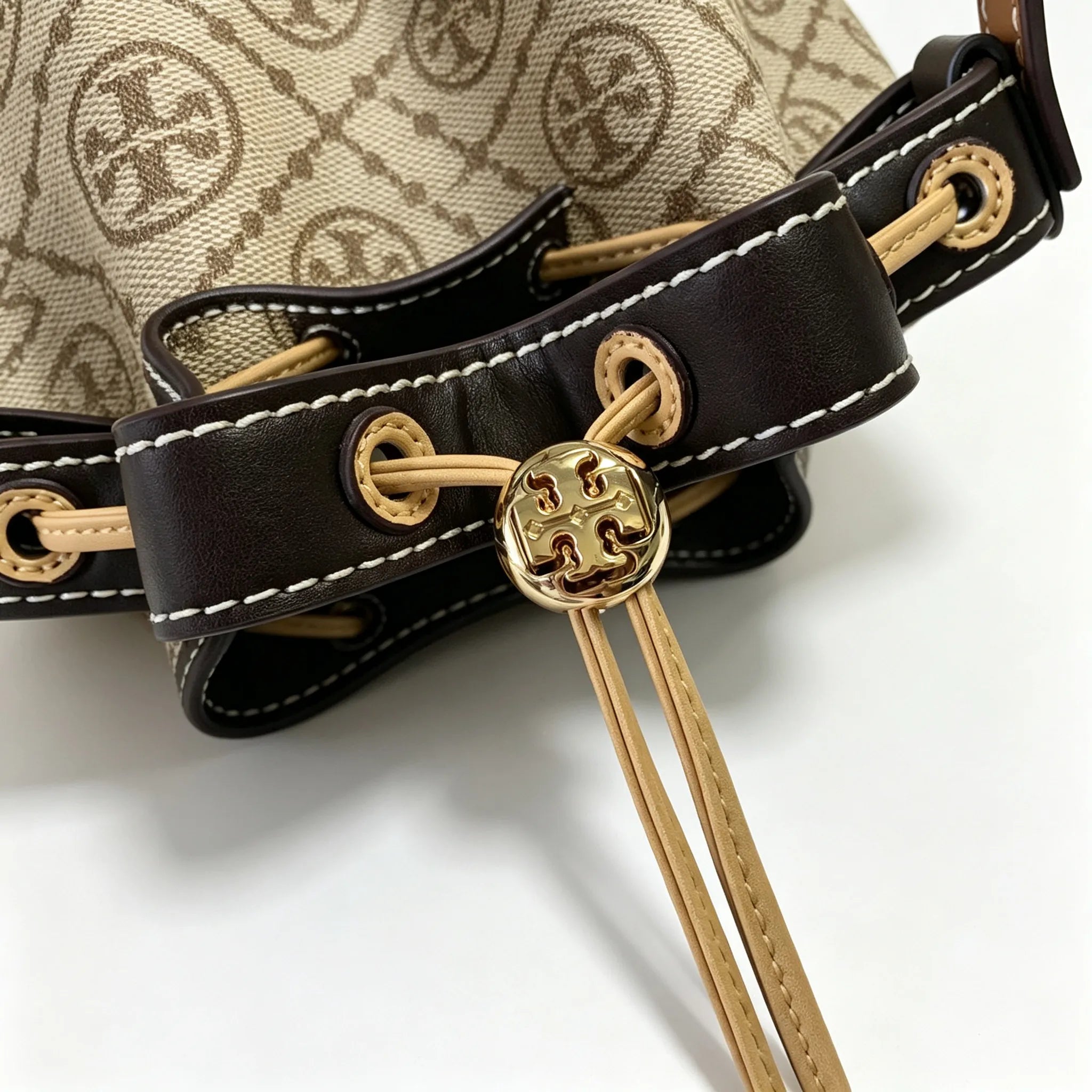 Tory Burch T Monogram | Off-white base with hazelnut brown monogram jacquard pattern and dark brown leather trim  drawstring closure versatile handbag suitable for commuting and travel