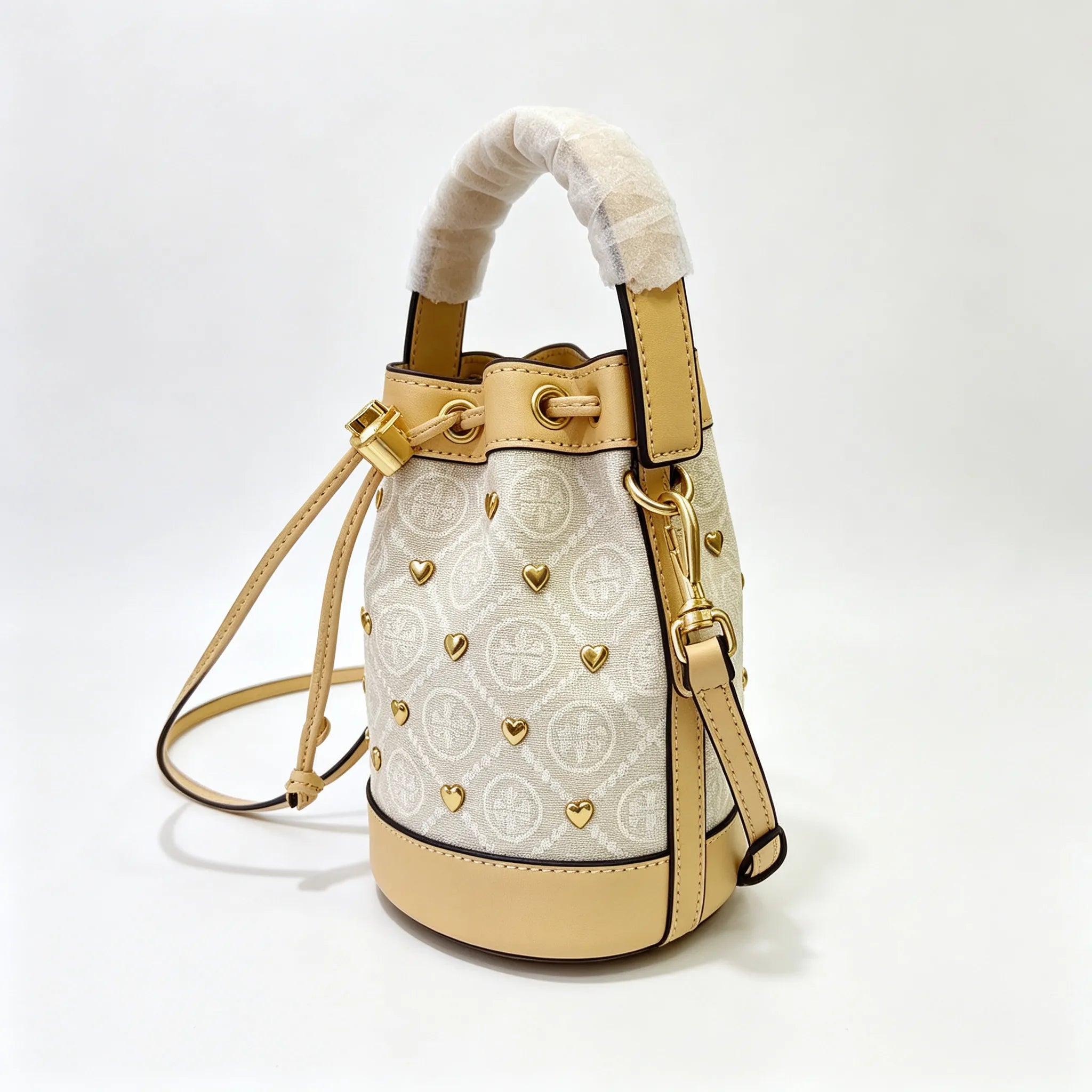 Tory Burch T Monogram ivory and beige Monogram canvas adorned with gold heart studs drawstring closure and detachable shoulder strap women's designer handbag