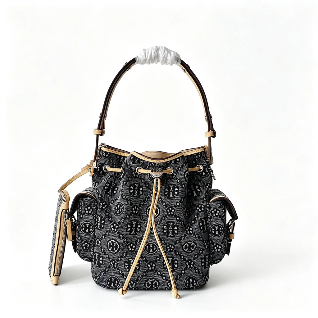 Tory Burch | Dark washed denim bucket bag with side pockets and drawstring closure featuring a T-print pattern