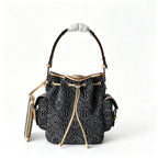 Tory Burch | Dark washed denim bucket bag with side pockets and drawstring closure featuring a T-print pattern