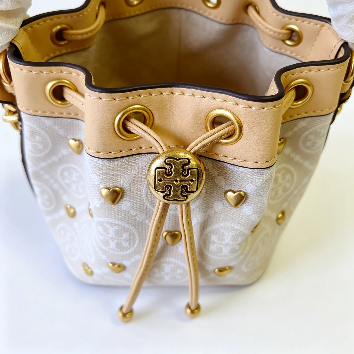 Tory Burch T Monogram ivory and beige Monogram canvas adorned with gold heart studs drawstring closure and detachable shoulder strap women's designer handbag